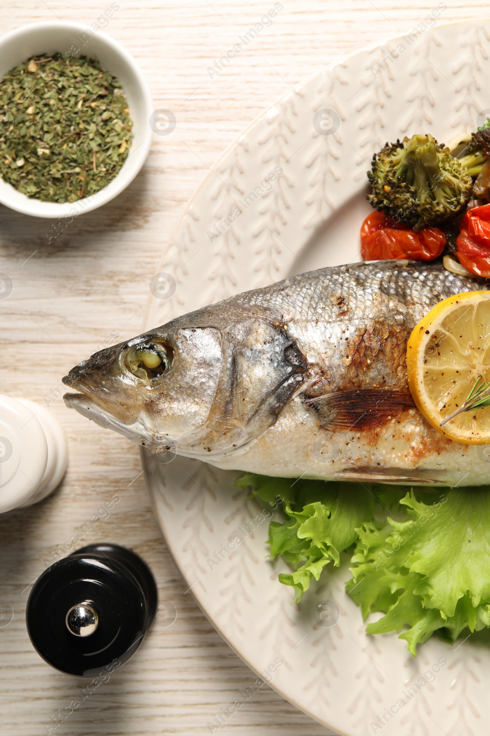 Photo of Delicious baked fish and vegetables served on wooden table, flat lay