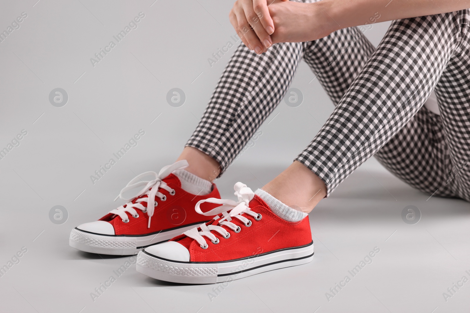 Photo of Woman wearing red classic old school sneakers on light grey background, closeup