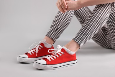 Woman wearing red classic old school sneakers on light grey background, closeup