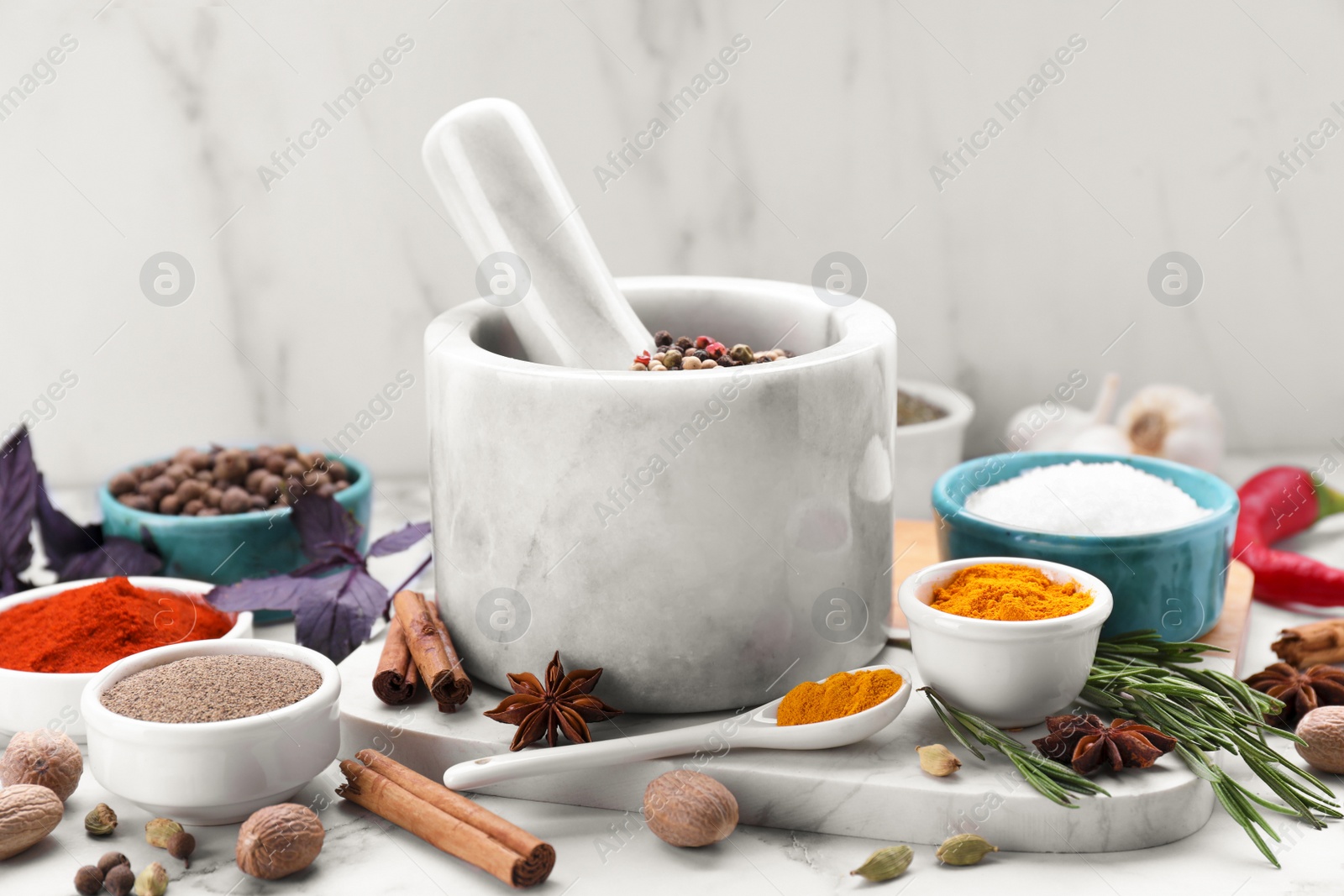 Photo of Mortar and different spices on white marble table