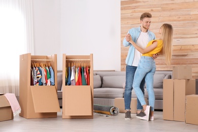 Happy young couple dancing near wardrobe boxes indoors