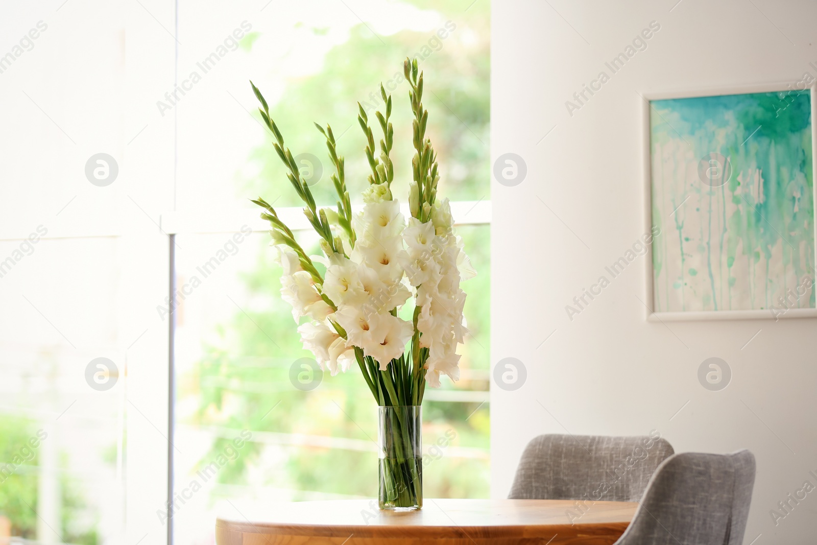 Photo of Vase with beautiful white gladiolus flowers on wooden table in room, space for text