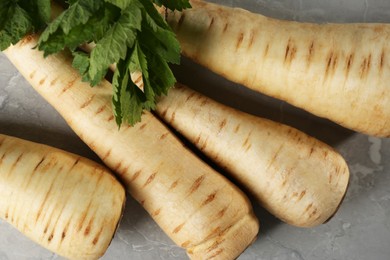 Many fresh ripe parsnips on grey marble table, flat lay