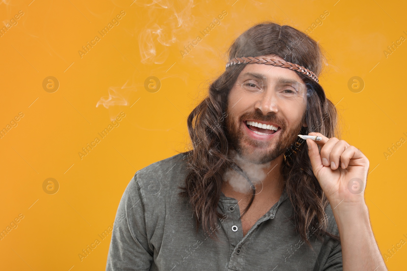 Photo of Hippie man smoking cigarette on orange background