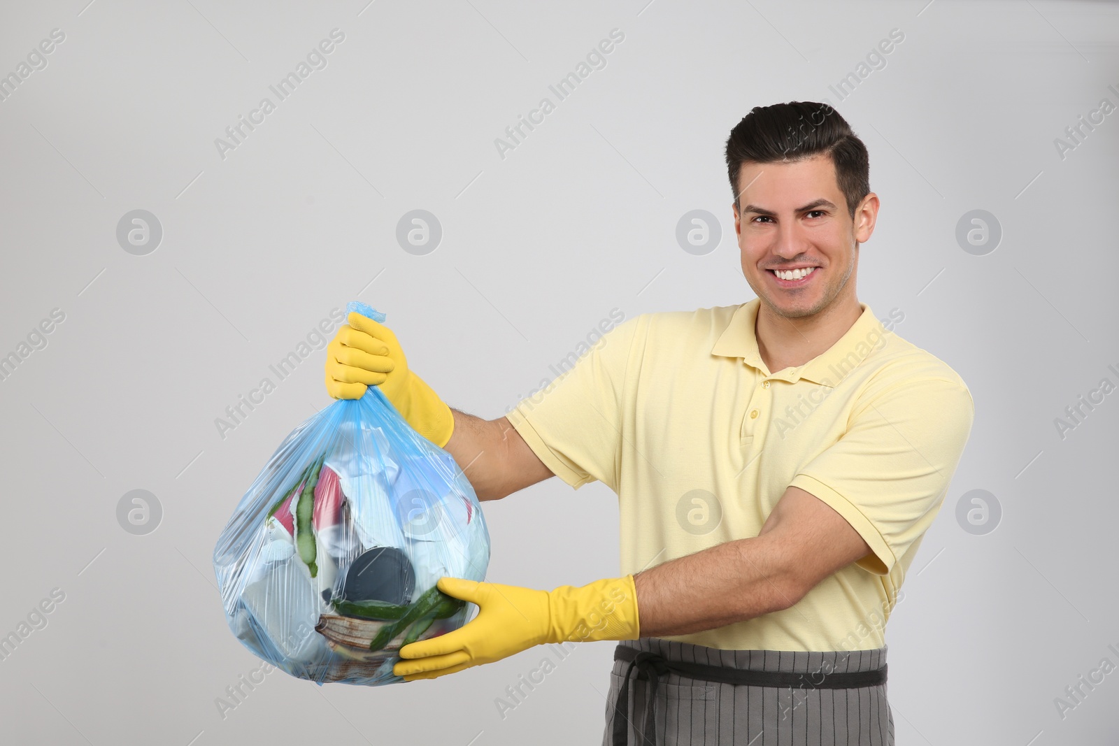 Photo of Man holding full garbage bag on light background