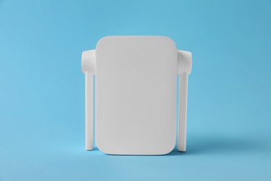 Photo of New modern Wi-Fi repeater on light blue background