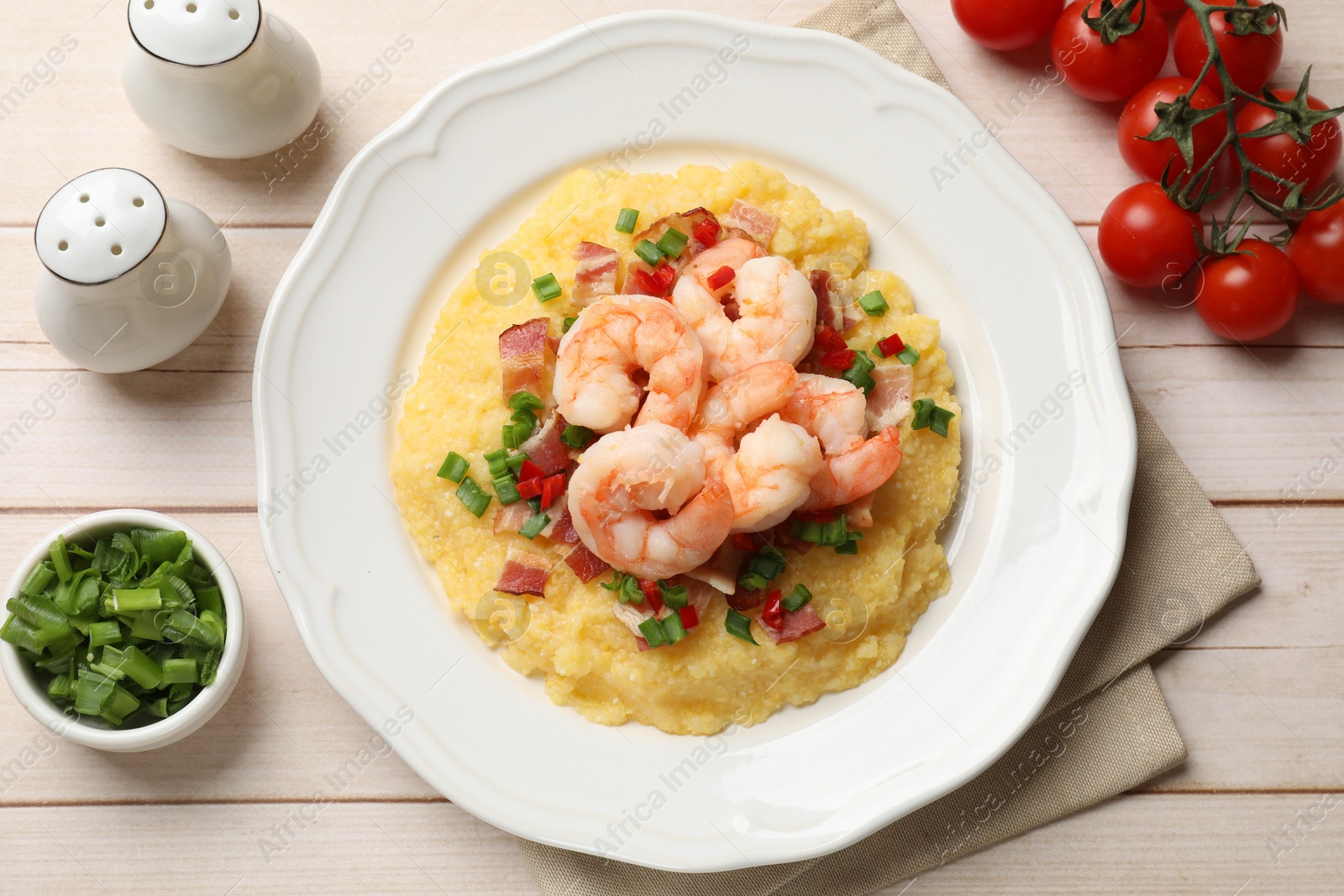 Photo of Plate with fresh tasty shrimps, bacon, grits, green onion and pepper on wooden table, flat lay