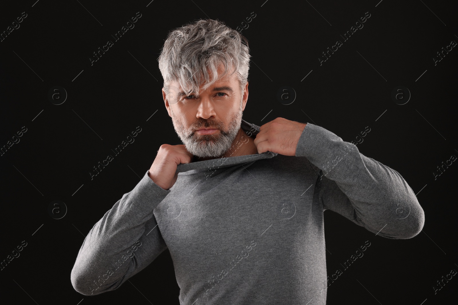 Photo of Portrait of confident man with beautiful hairstyle on black background