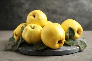Photo of Fresh ripe organic quinces with leaves on grey table