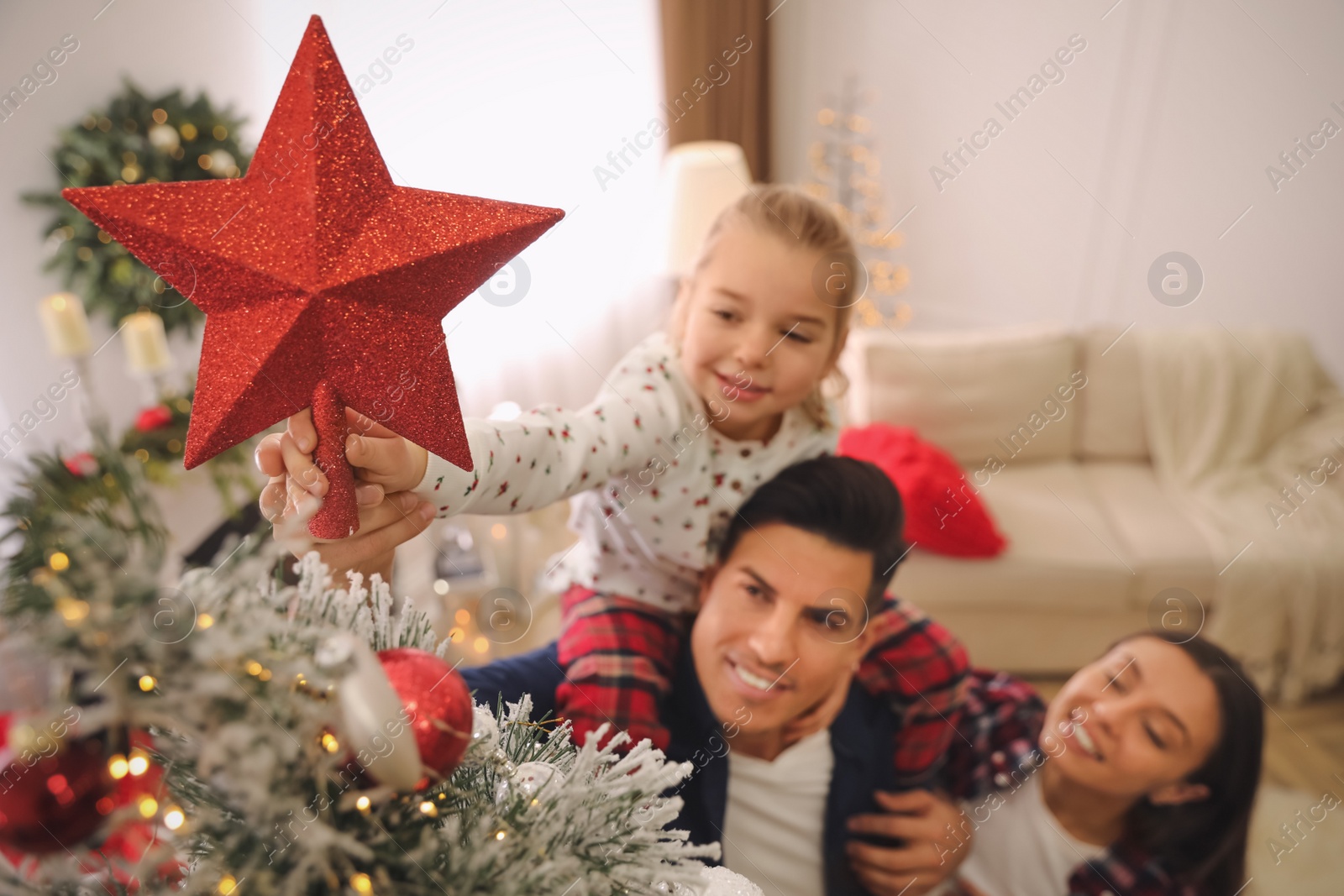 Photo of Family decorating Christmas tree indoors, focus on star topper