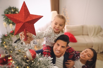 Photo of Family decorating Christmas tree indoors, focus on star topper