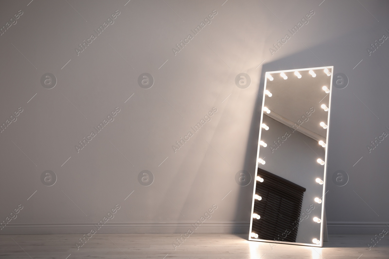 Photo of Stylish mirror with light bulbs near white wall indoors. Interior element