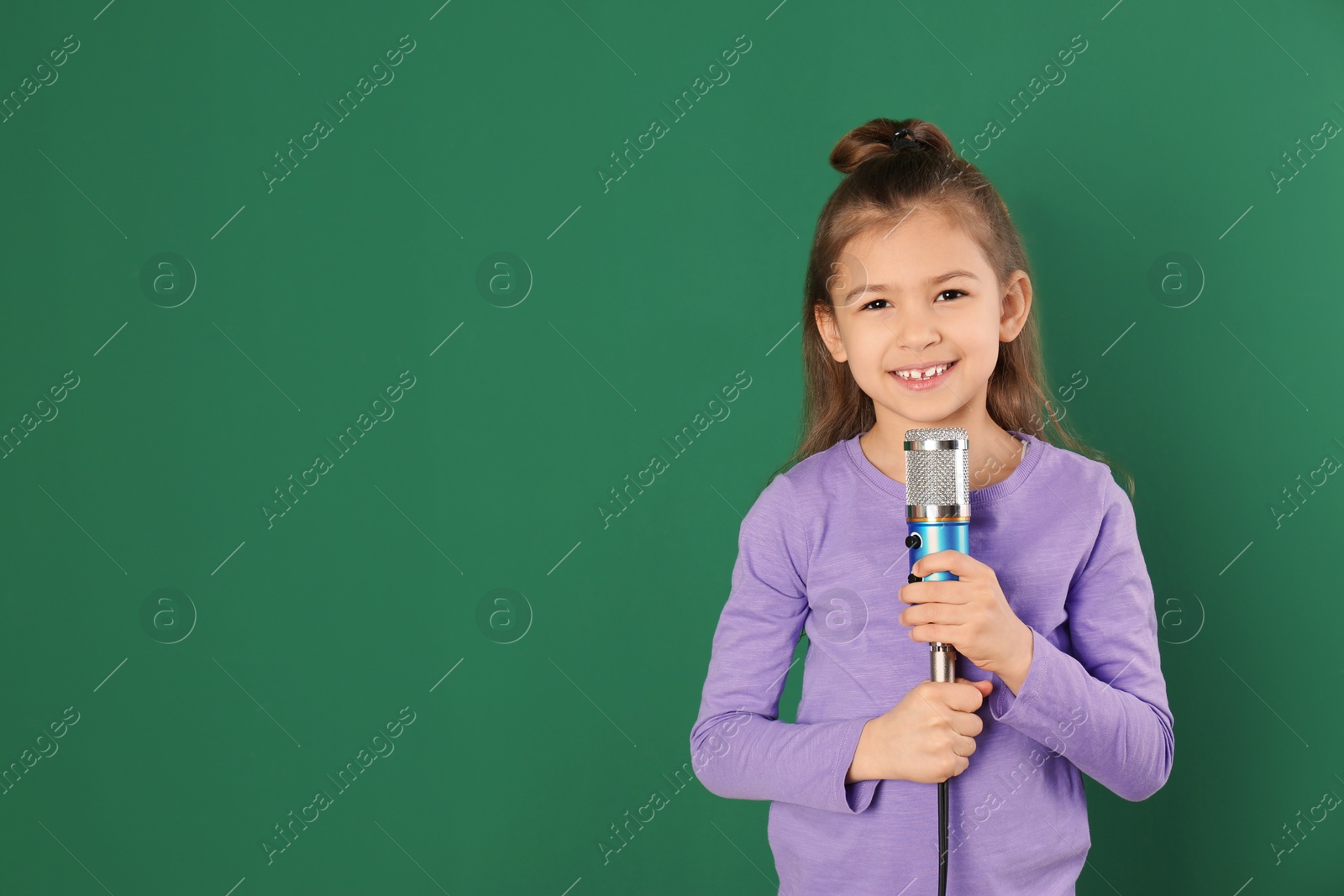 Photo of Cute funny girl with microphone on color background. Space for text