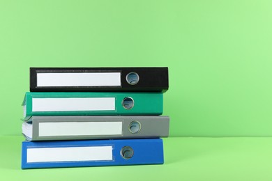 Photo of Stack of office folders on light green background, space for text