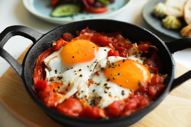 Tasty Shakshouka served in pan on table, closeup