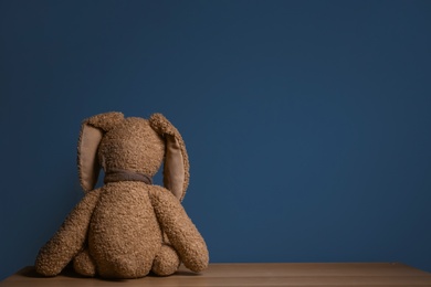 Photo of Abandoned toy bunny on table against dark background. Time to visit child psychologist
