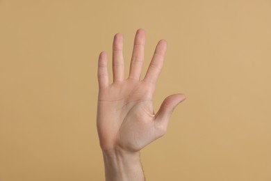 Photo of Man giving high five on beige background, closeup of hand