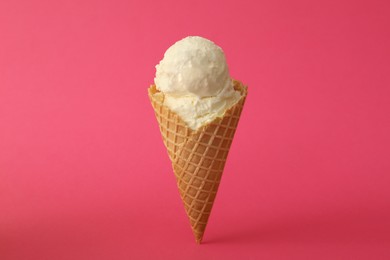 Photo of Delicious ice cream in waffle cone on pink background