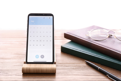 Smartphone with calendar app on wooden table