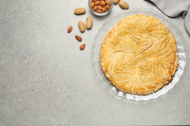Traditional galette des rois and almonds on grey table, flat lay. Space for text