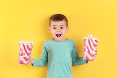 Photo of Cute little boy with popcorn on color background