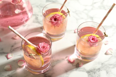 Refreshing drink with lemon and rose on white marble table