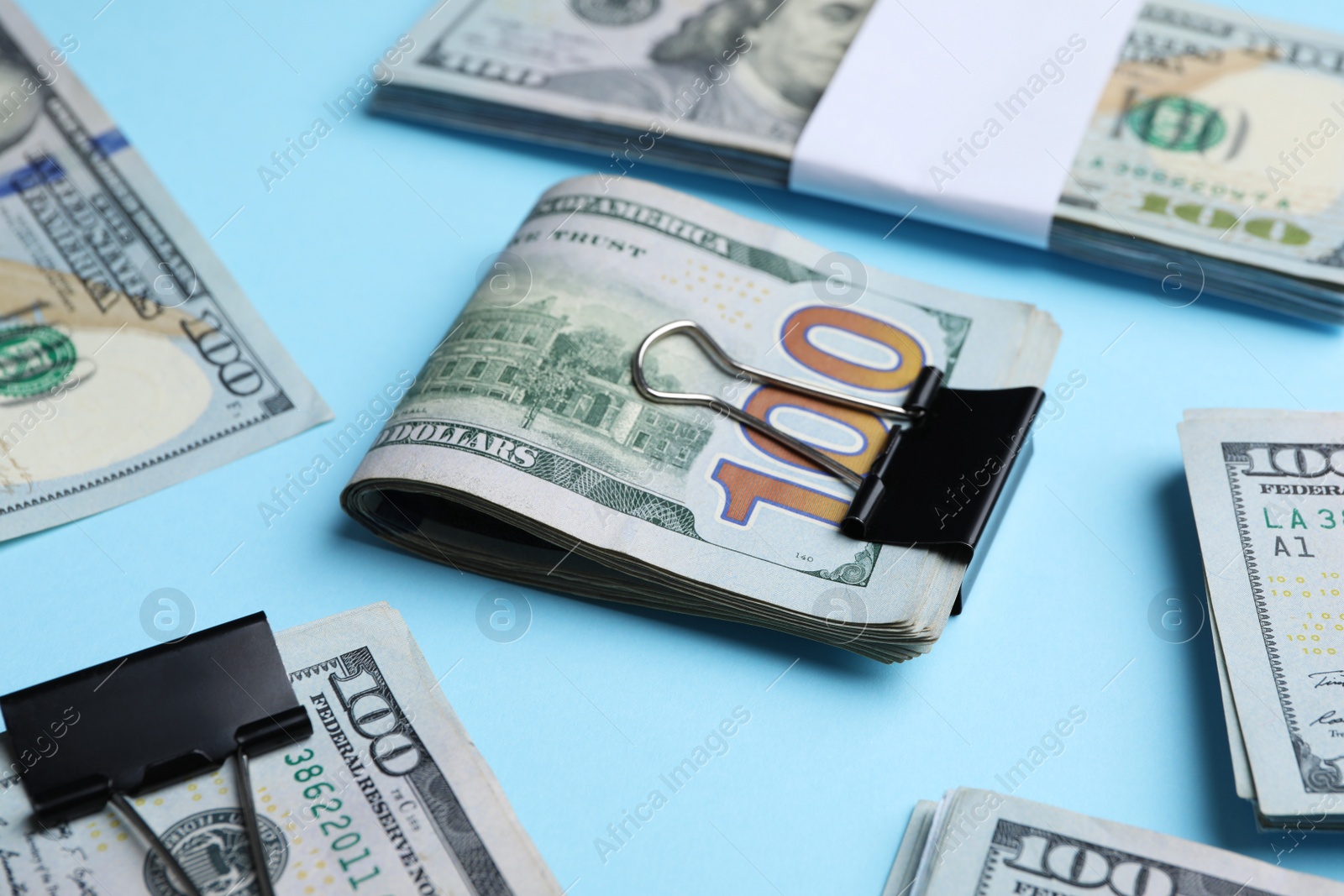 Photo of Many dollar banknotes with paper clips on light blue background