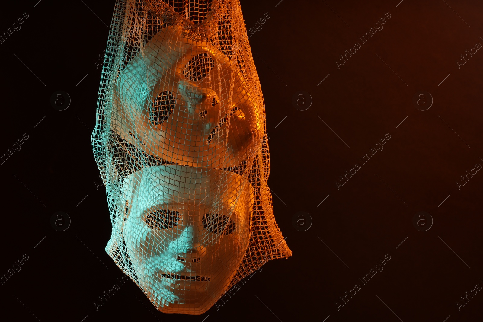 Photo of Net bag with plastic face masks on black background, space for text. Theatrical performance
