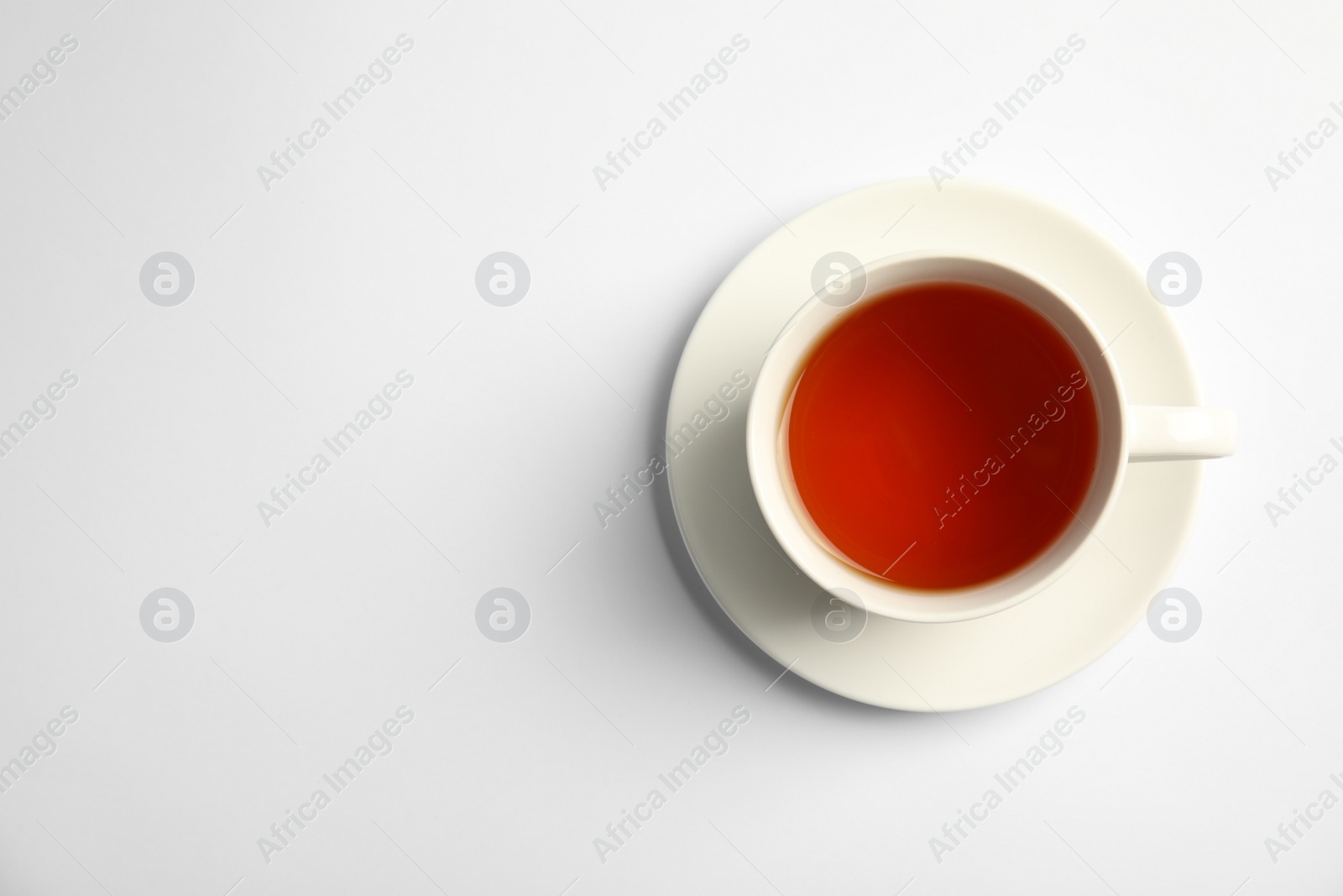 Photo of Cup of delicious tea with saucer on white background, top view