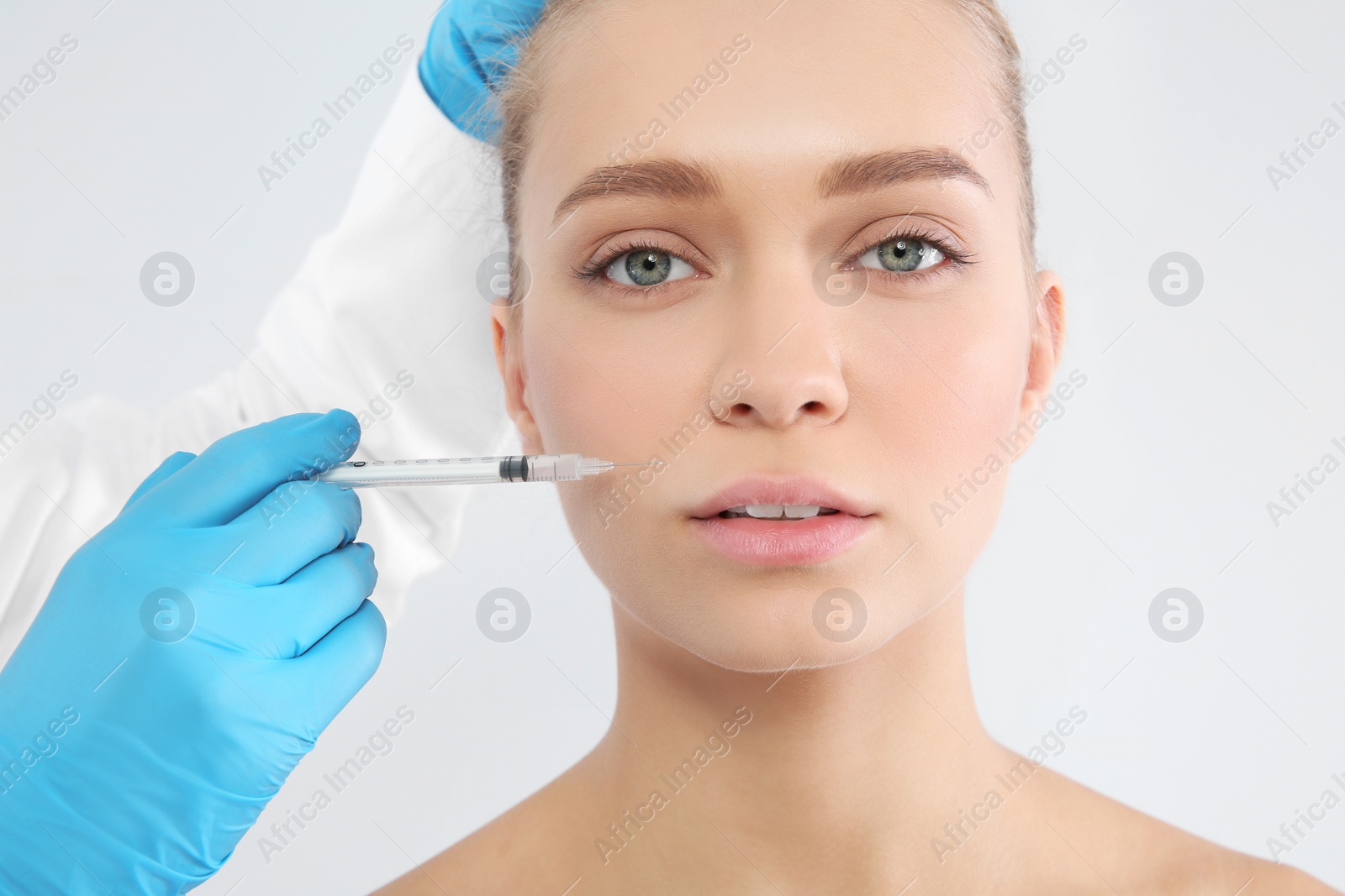 Photo of Young woman getting facial injection on white background. Cosmetic surgery concept