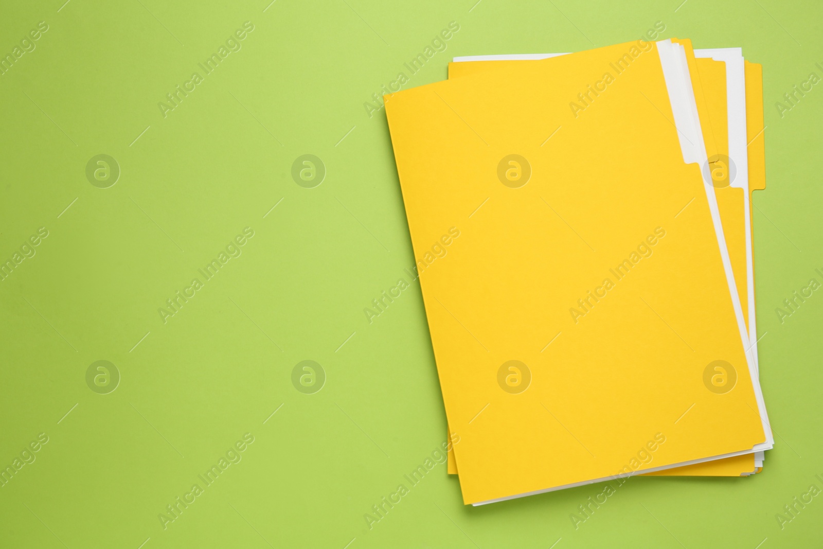Photo of Yellow files with documents on light green background, top view. Space for text