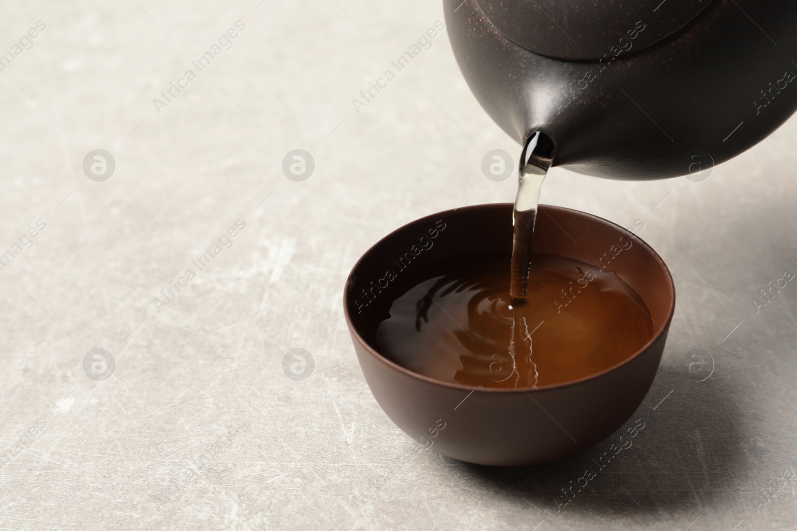 Photo of Pouring Tie Guan Yin oolong tea into cup on light table. Space for text
