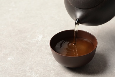 Photo of Pouring Tie Guan Yin oolong tea into cup on light table. Space for text
