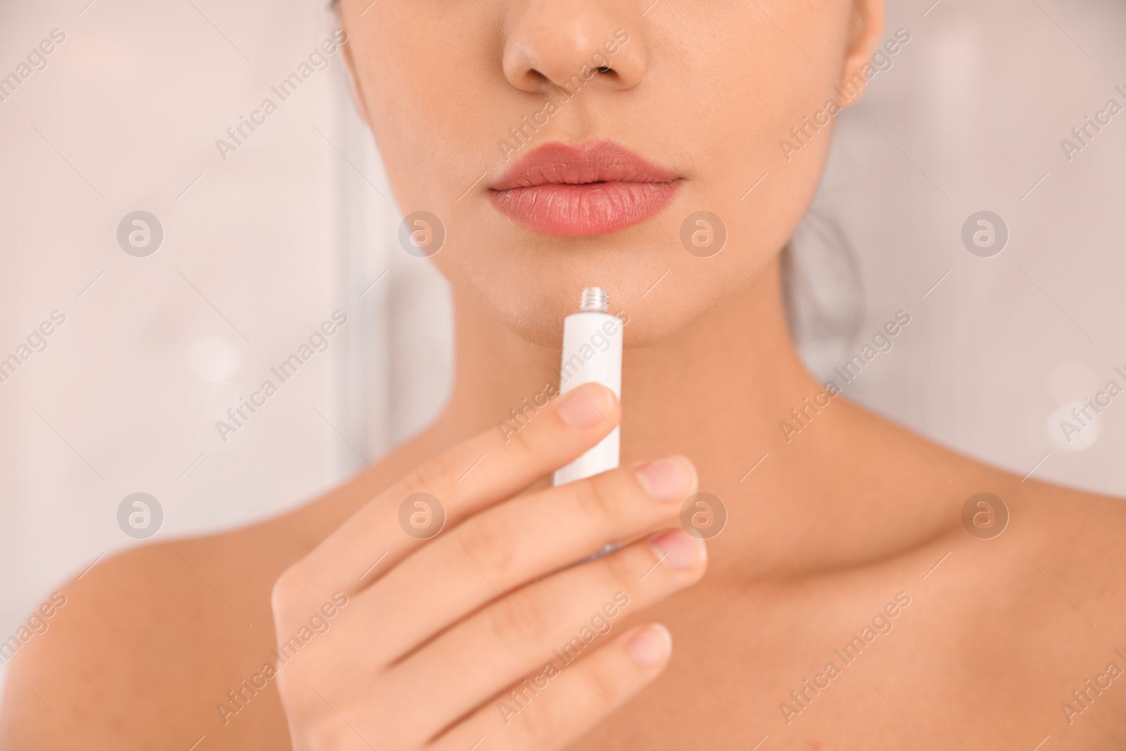 Photo of Woman with herpes applying cream on lips against blurred background, closeup