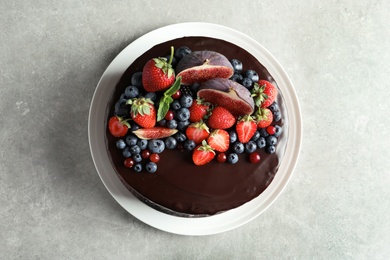 Fresh delicious homemade chocolate cake with berries on gray table, top view