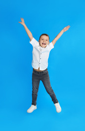 Photo of Cute little boy jumping on blue background