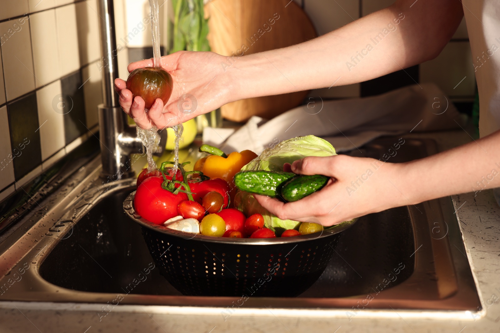 Photo of Woman washing different vegetables in metal colander, closeup