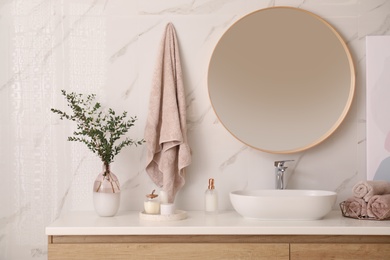 Photo of Vase with beautiful branches and fresh towels near vessel sink in bathroom. Interior design