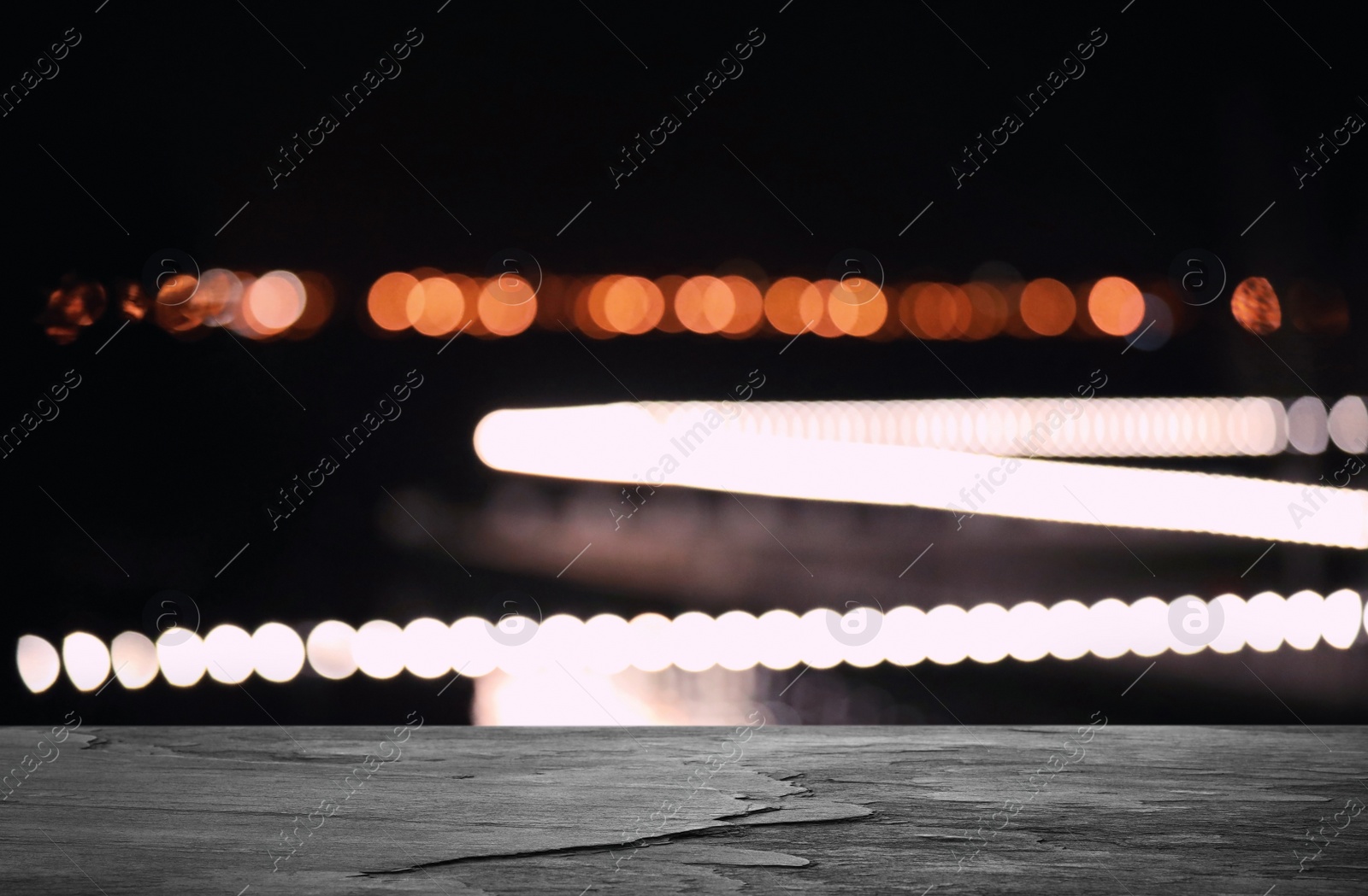 Image of Empty black stone surface and blurred view of night city. Bokeh effect 