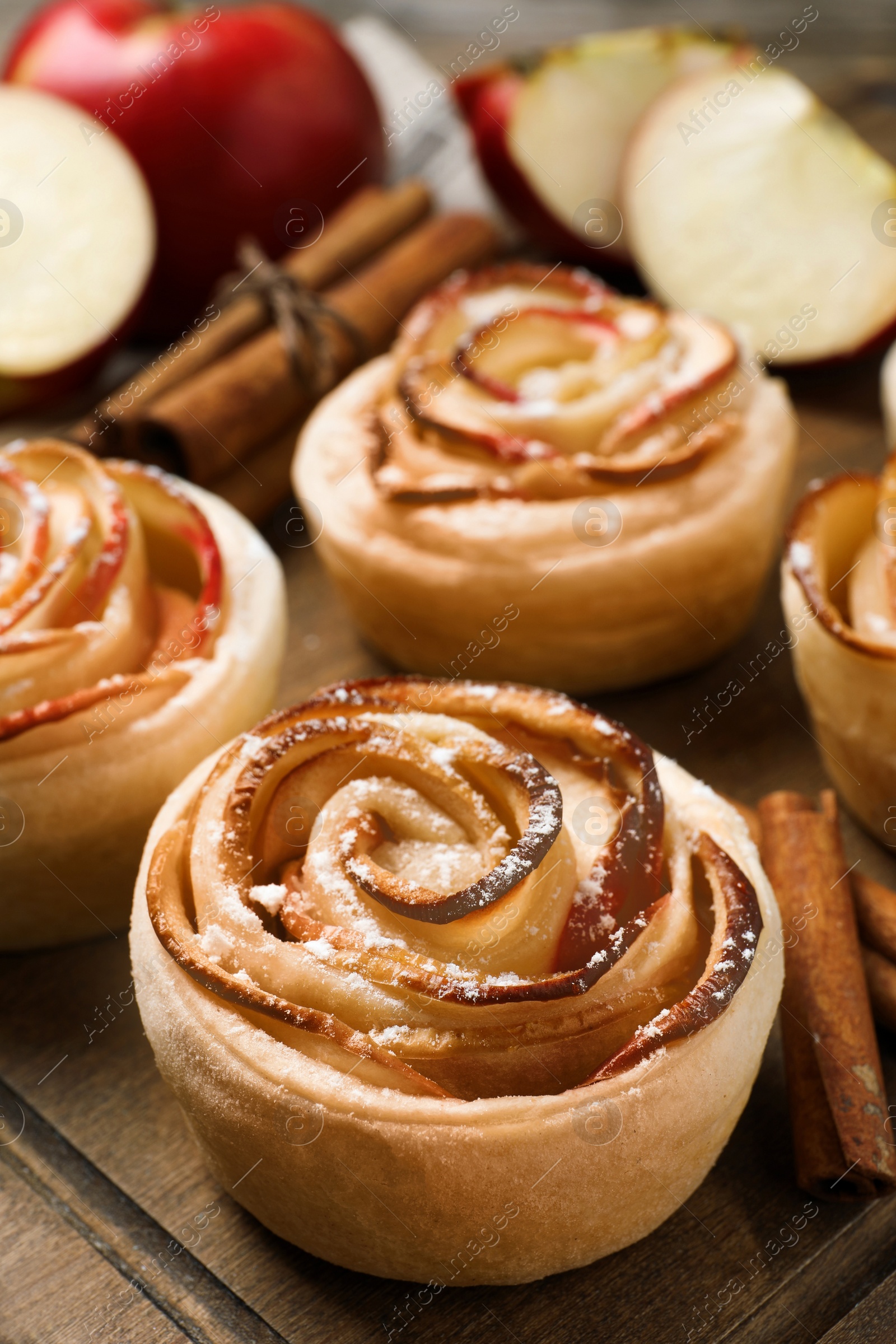 Photo of Freshly baked apple roses on wooden table, closeup. Beautiful dessert