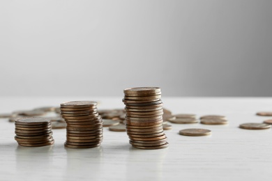 Photo of Stacked coins on white wooden table against light background