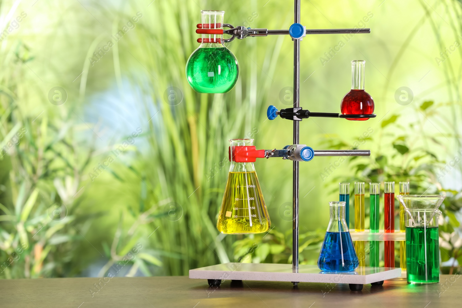 Photo of Laboratory glassware with colorful liquids on table against blurred background. Space for text