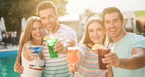 Image of Happy young friends with fresh summer cocktails relaxing near swimming pool. Banner design