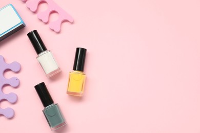 Photo of Nail polishes, toe separators and buffer on pink background, flat lay. Space for text