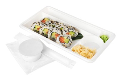 Food delivery. Plastic container with delicious sushi rolls near bowl of soy sauce and chopsticks on white background