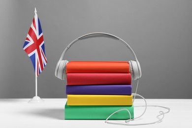 Learning foreign language. Flag of United Kingdom, books and headphones on white table