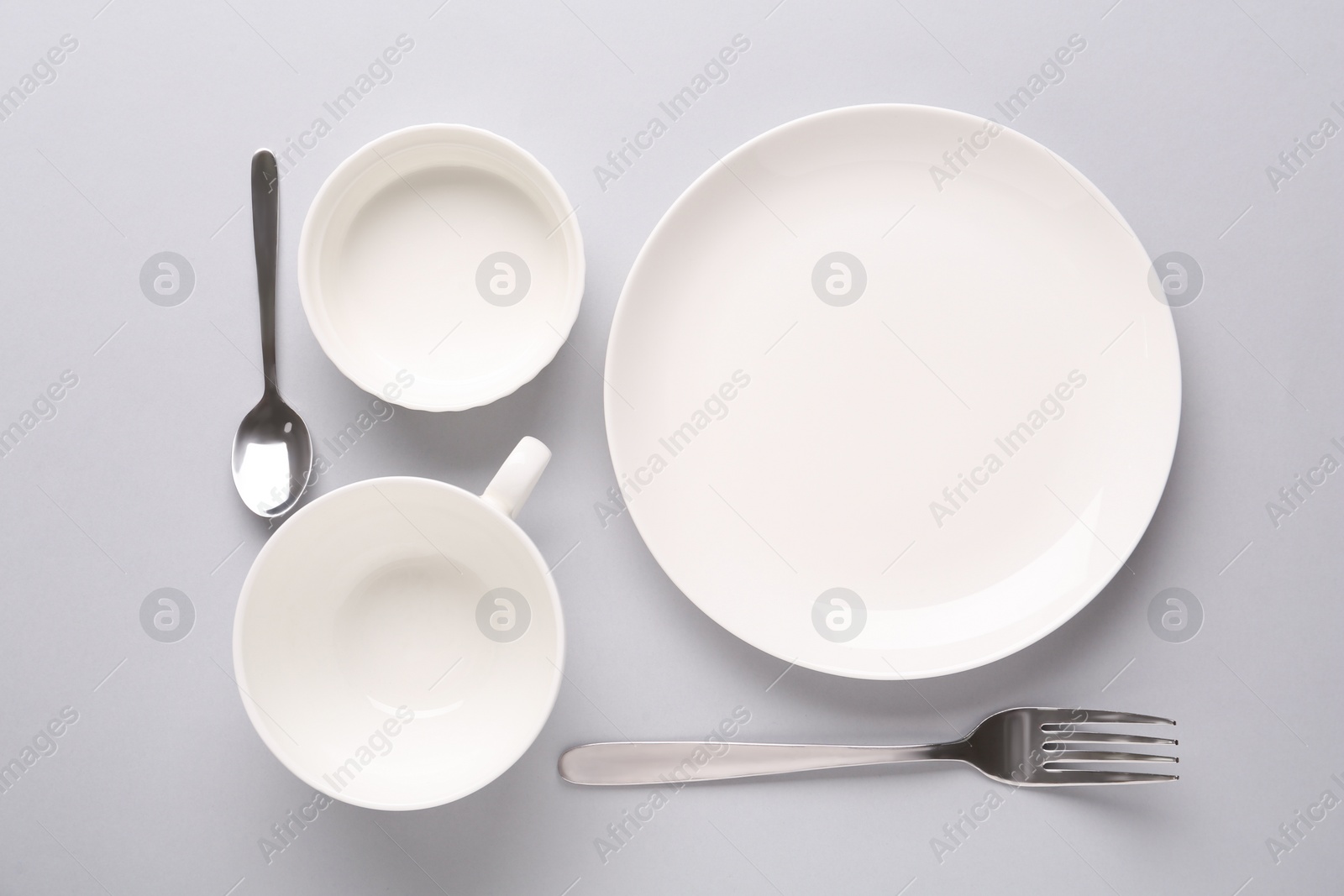 Photo of Set of empty clean tableware on grey background, flat lay