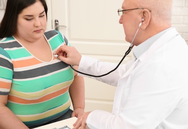Doctor listening to patient's heartbeat with stethoscope in clinic