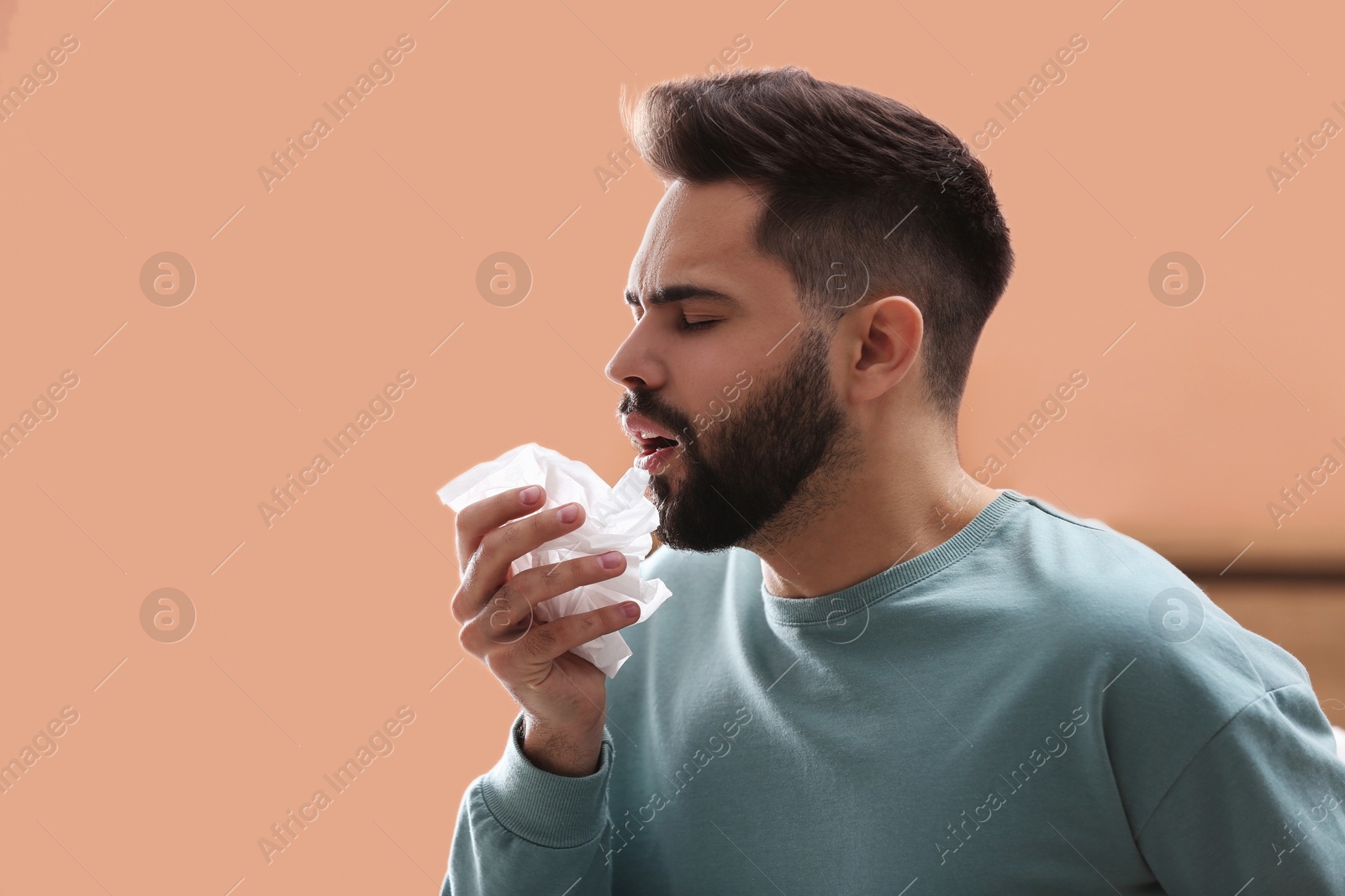 Photo of Young man suffering from runny nose indoors