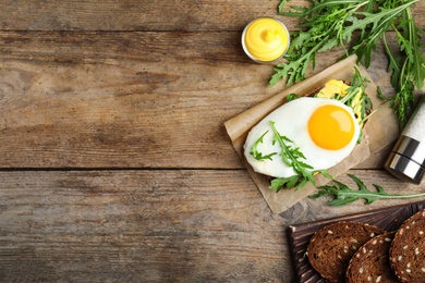 Photo of Delicious sandwich with arugula and egg on wooden table, flat lay. Space for text